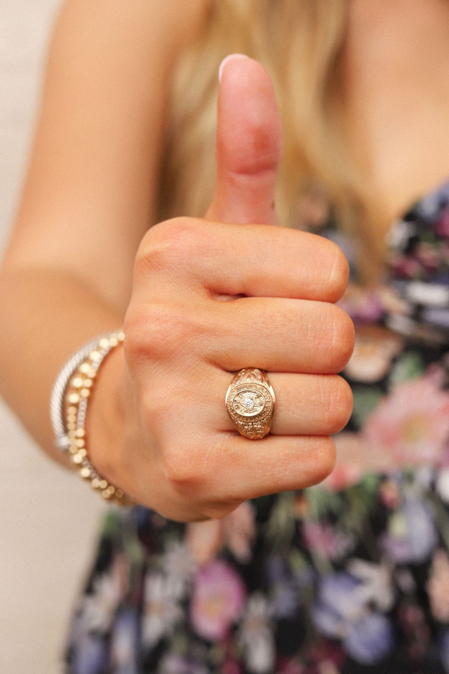 Close-up of a hand giving thumbs up showing jewelry and ring details.