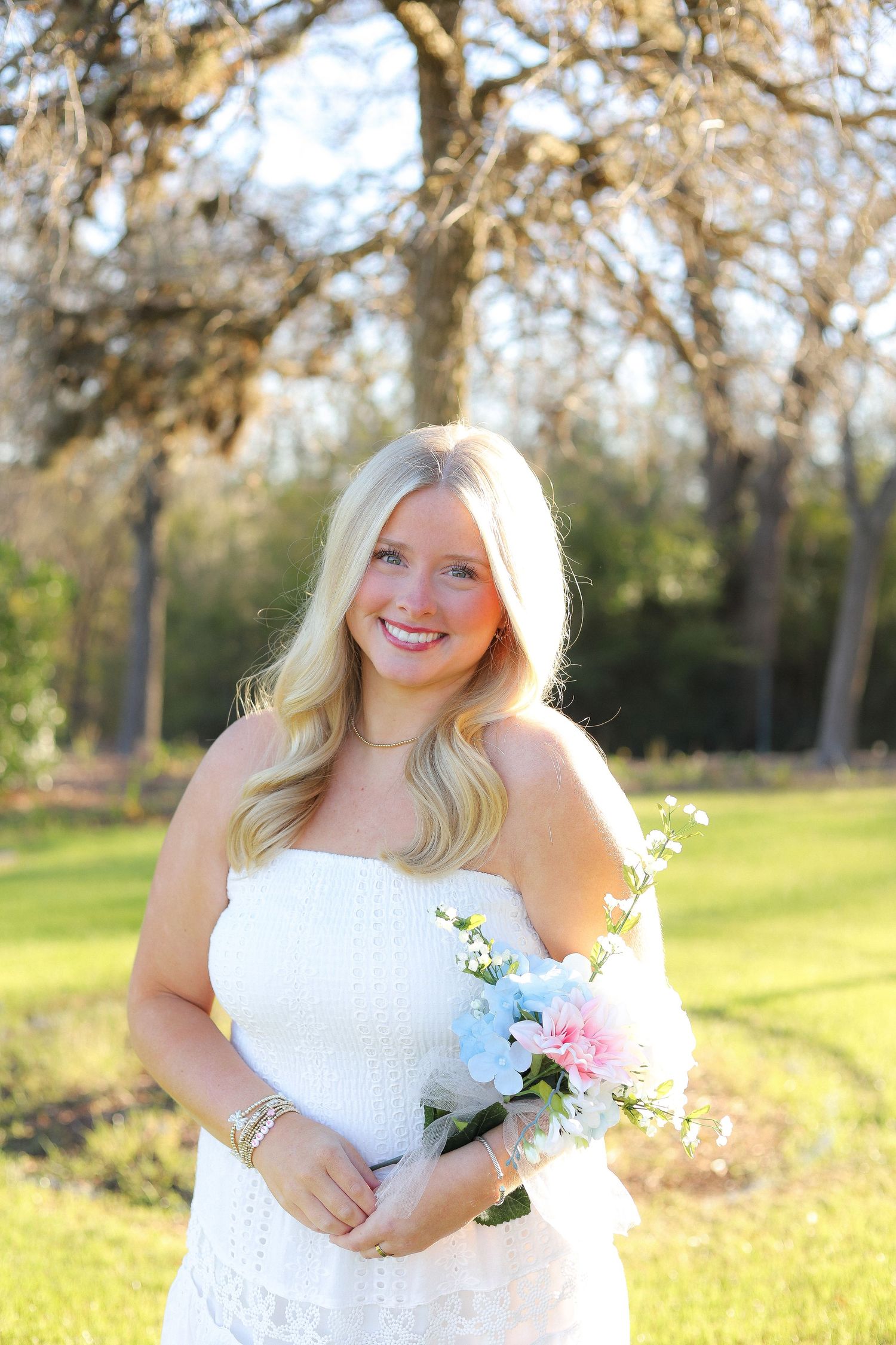 A series of joyful outdoor portrait shots in a white dress holding delicate flowers against a sunlit natural backdrop.