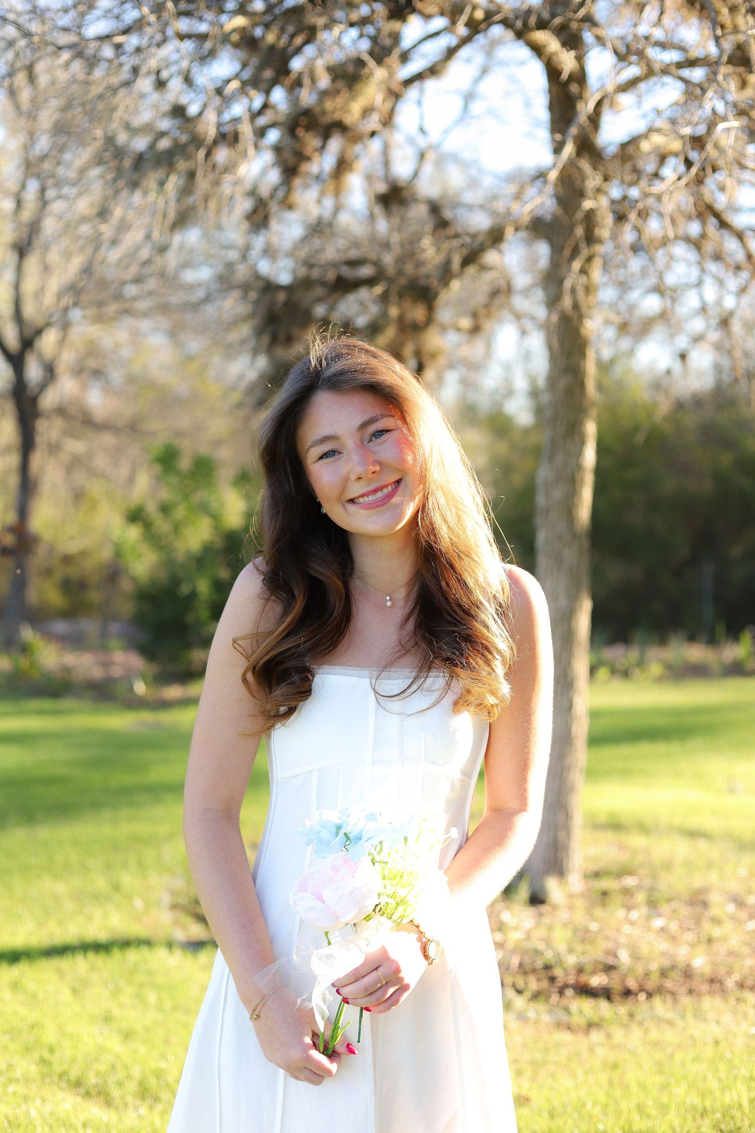 A person wearing a white sundress stands in a grassy field during golden hour.