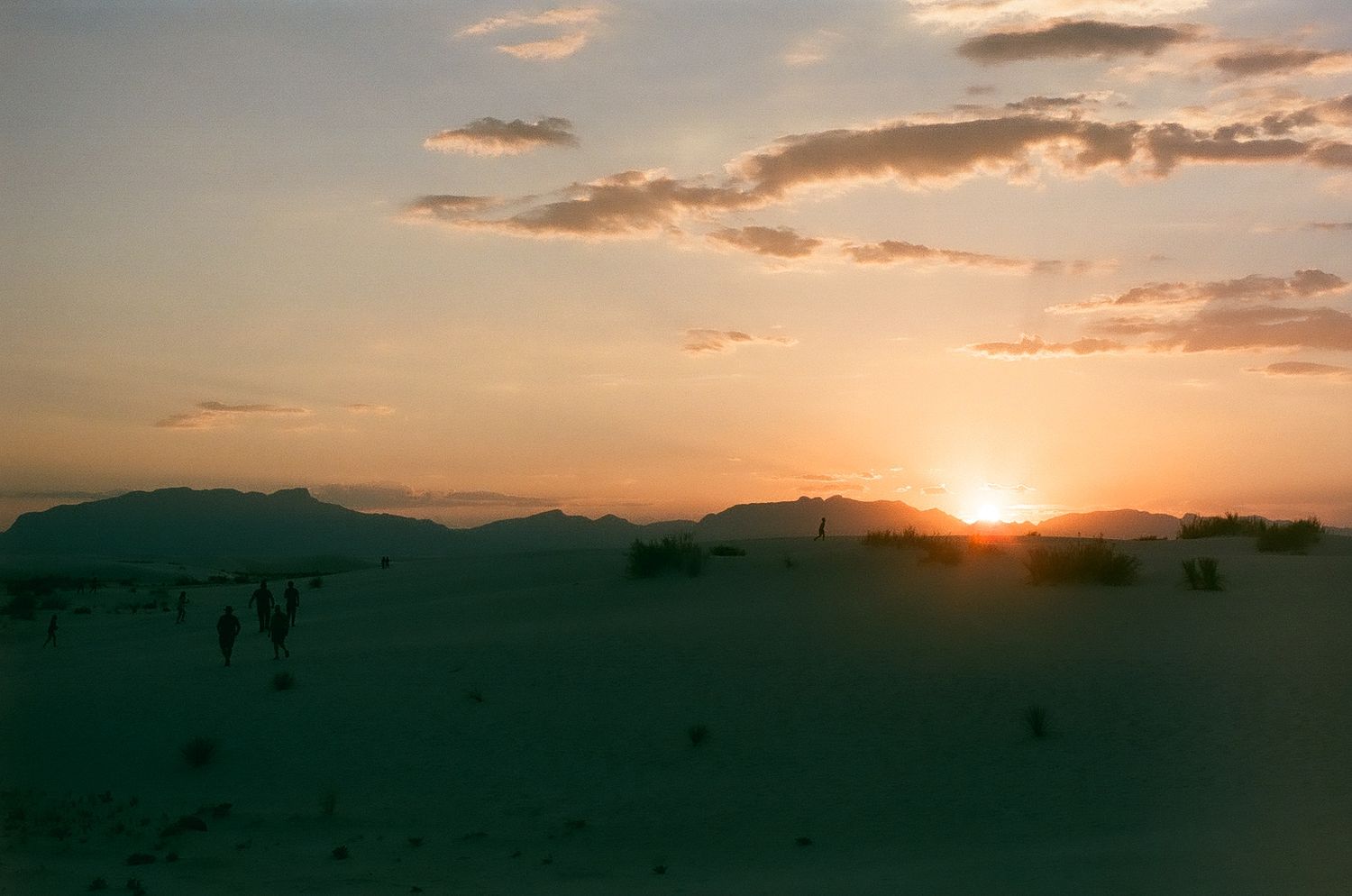 Dramatic panoramic view of a desert landscape during golden hour with mountains in silhouette.