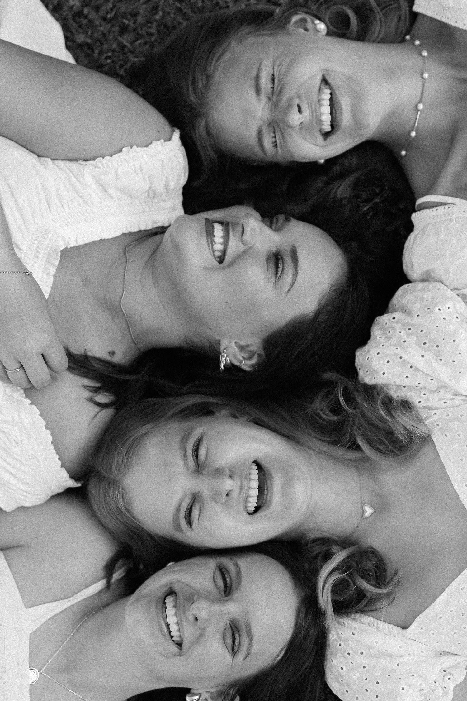 Black and white close-up of friends lying together with happy expressions.