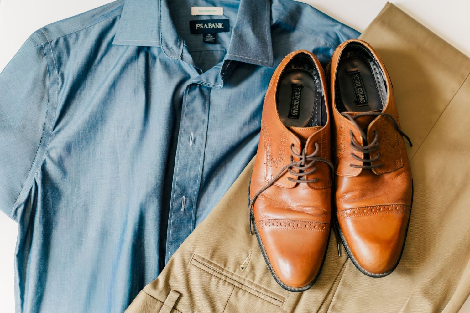Men’s outfit with blue button-down shirt, khaki pants, and brown dress shoes for family photos