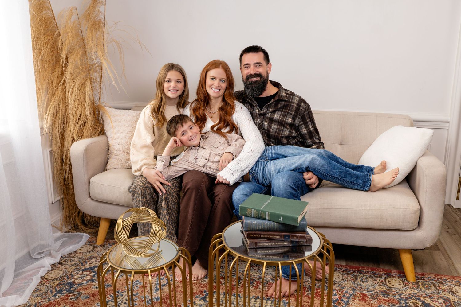 Family wearing coordinated neutral outfits sitting together on a couch during an in-home lifestyle photography session