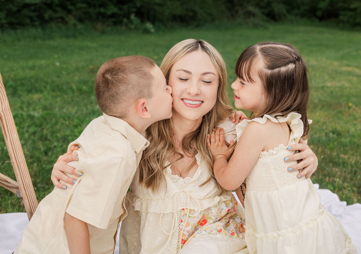 Mother smiling as her two children kiss her cheeks during an outdoor family photography session in Murfreesboro, Tennessee