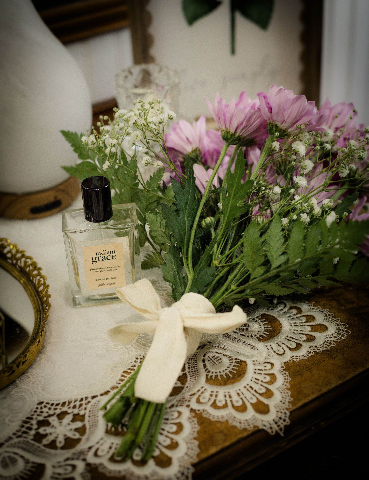Romantic detail photo of a pink wildflower bridal bouquet beside perfume and vintage lace decor during an intimate elopement in Murfreesboro