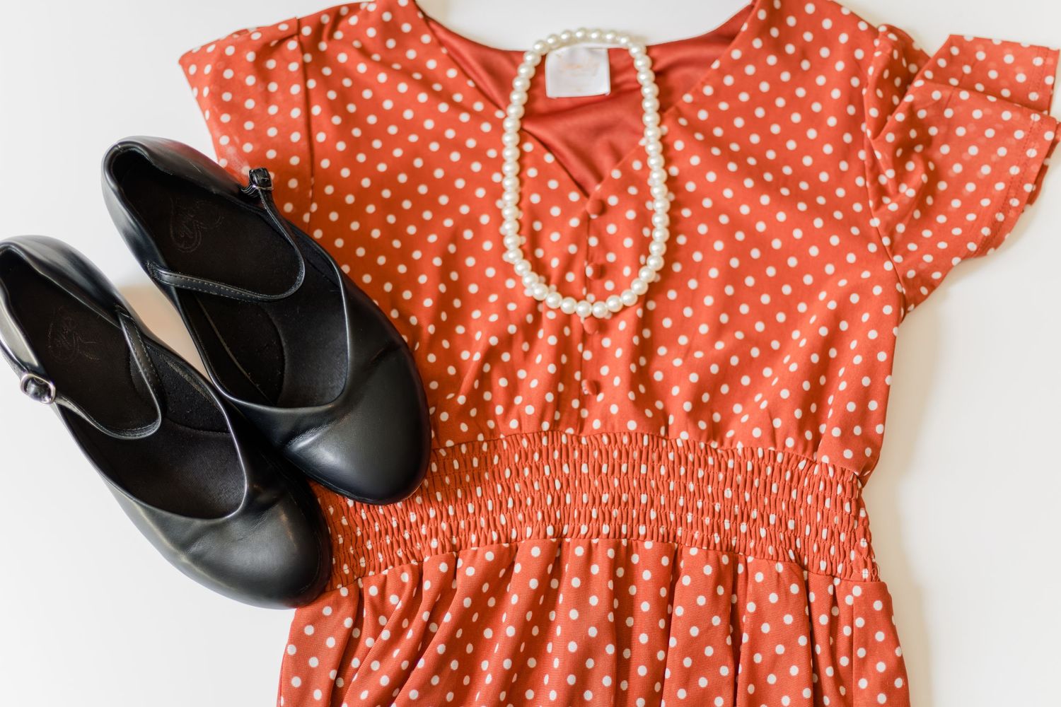 Orange polka dot dress with black shoes and pearl necklace styled as a family photo outfit idea