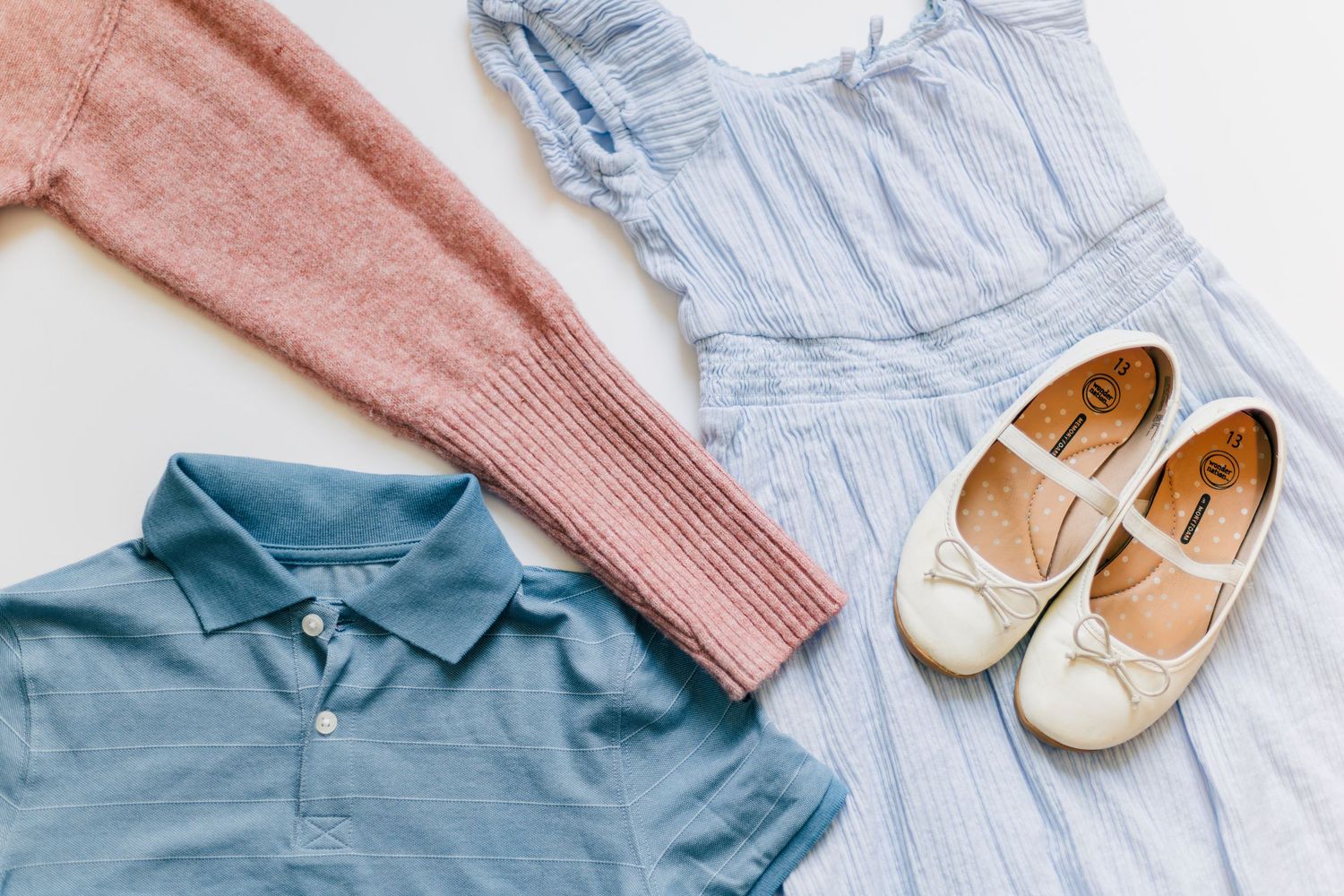 Kids spring outfit flatlay with blue dress, pink sweater, and ballet flats