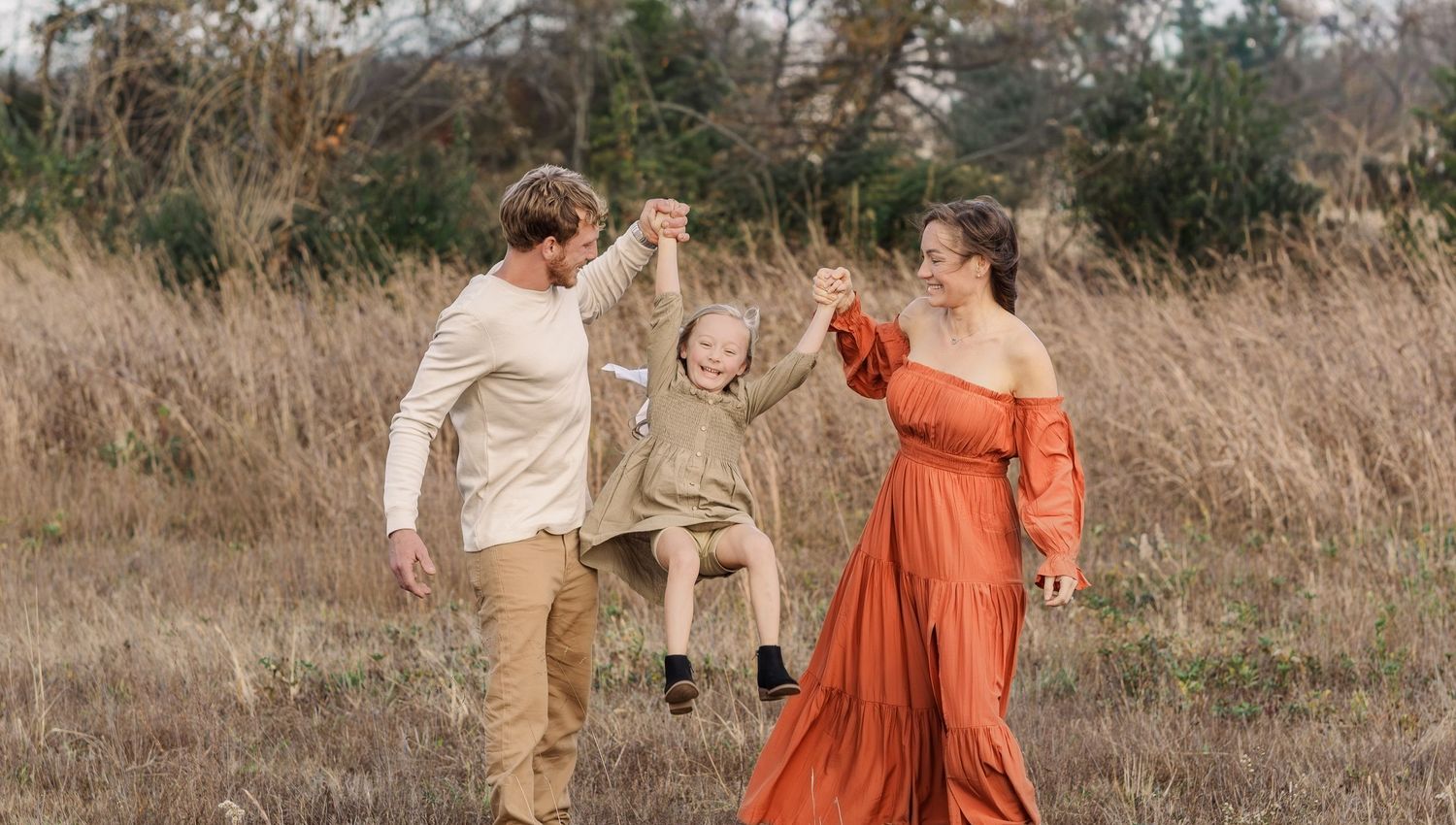 Family wearing coordinated earthy tones including rust, olive, and neutrals during an outdoor photography session