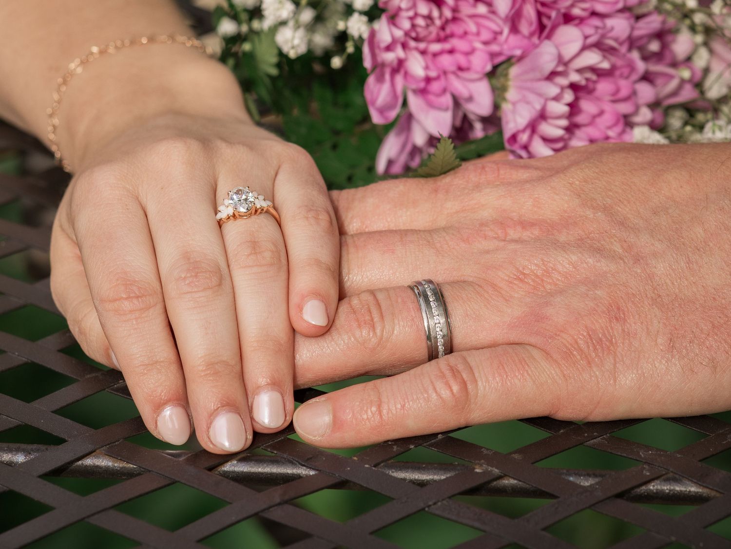 Close-up wedding ring detail photo of a bride and groom holding hands during an outdoor wedding in Murfreesboro, Tennessee with pink florals