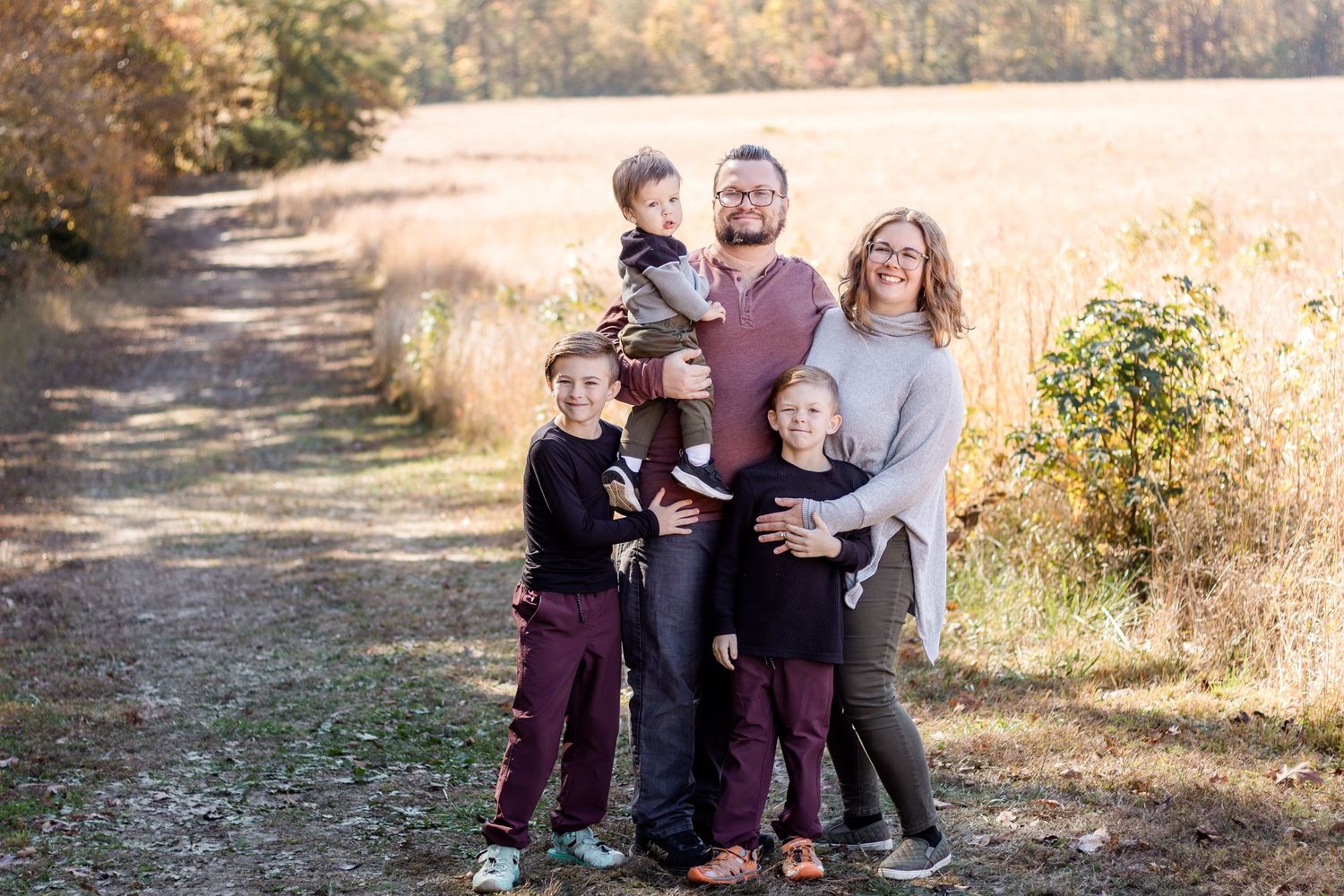Family wearing coordinated fall outfits in warm tones during an outdoor photography session in a field