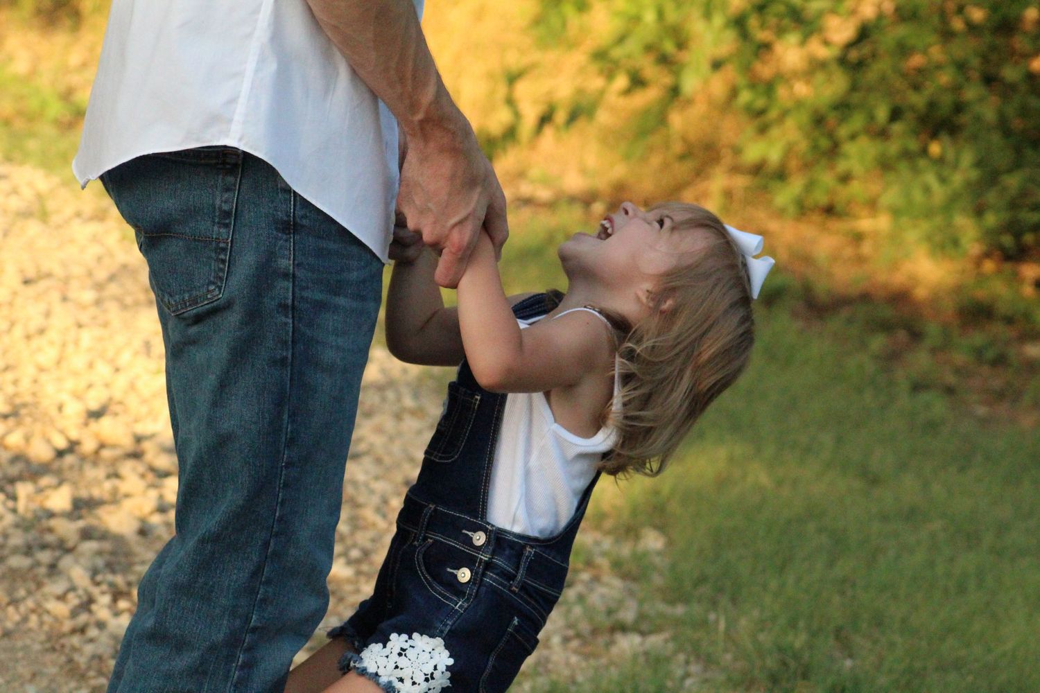 Father holding his daughter’s hands during a warm outdoor family session in Murfreesboro, Tennessee.
