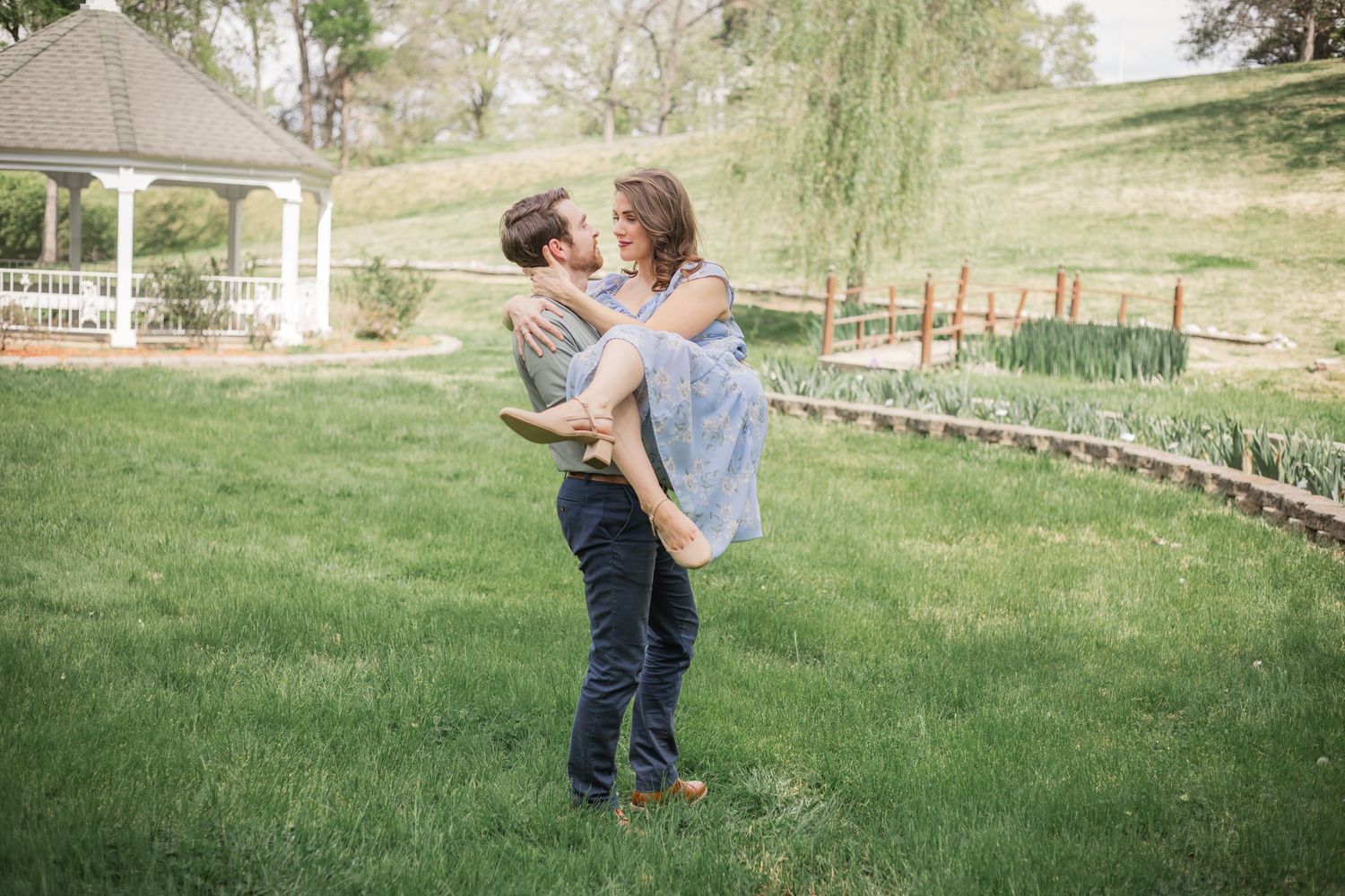 Couple sharing a quiet, romantic moment during a Murfreesboro, TN engagement session as he lifts her in a sunlit park.