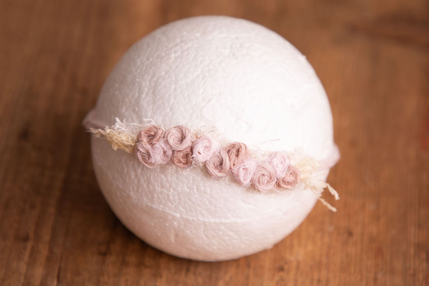 Dusty rose chiffon rosette headband on white ball newborn photography prop on wood.