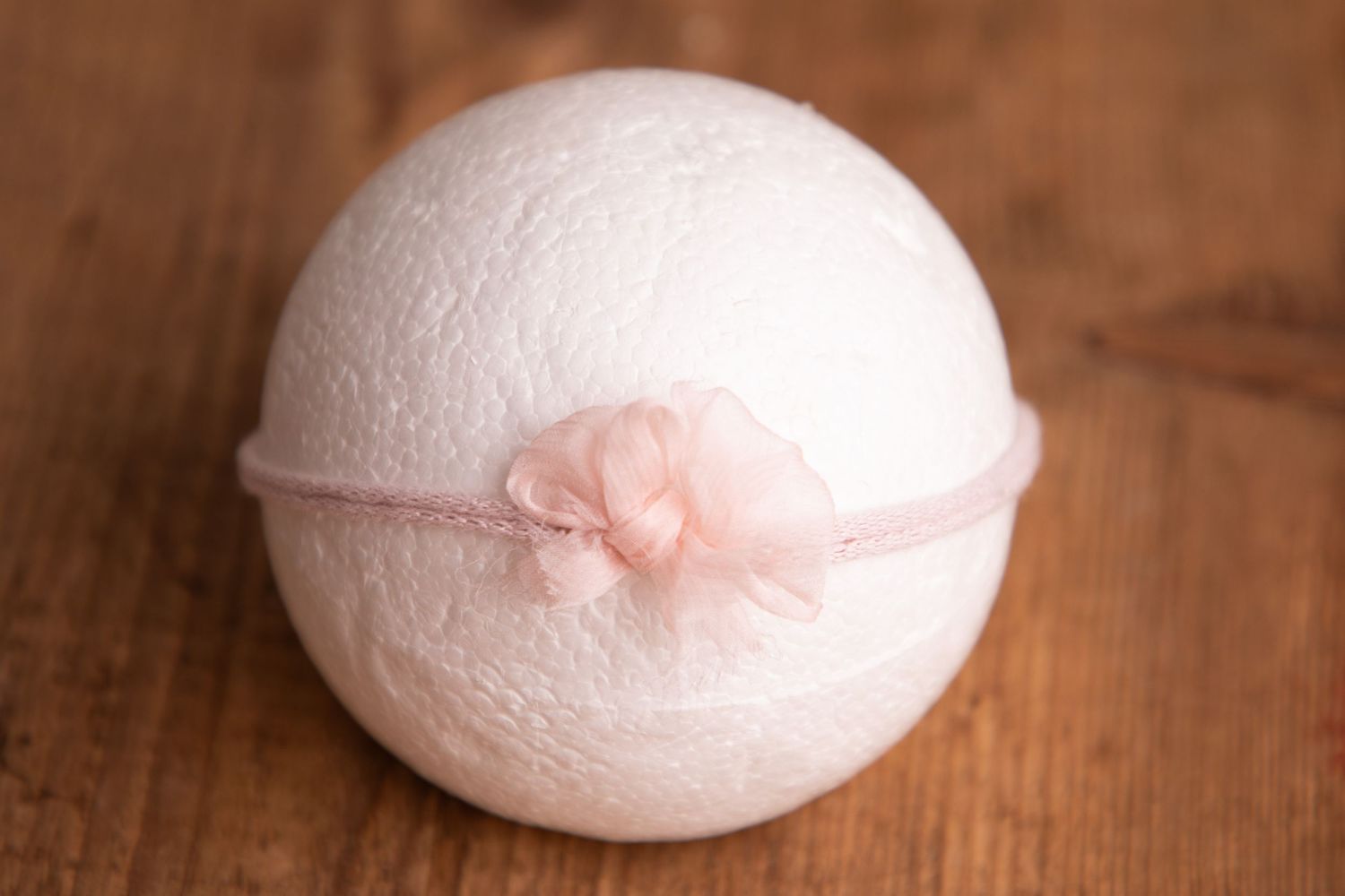 White wool felt ball with soft pink chiffon bow on blush elastic headband.