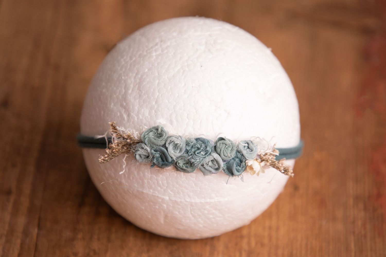 Teal blue rosette headband with gold star accents on white sphere newborn photography prop.