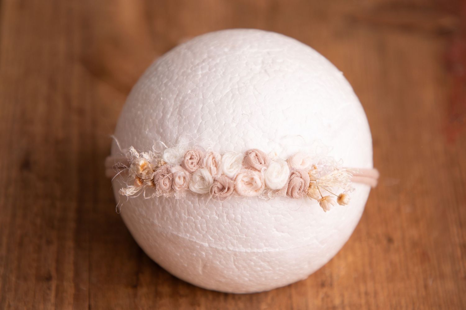 Blush mixed floral headband with pearls on white ball newborn photography prop on wood.