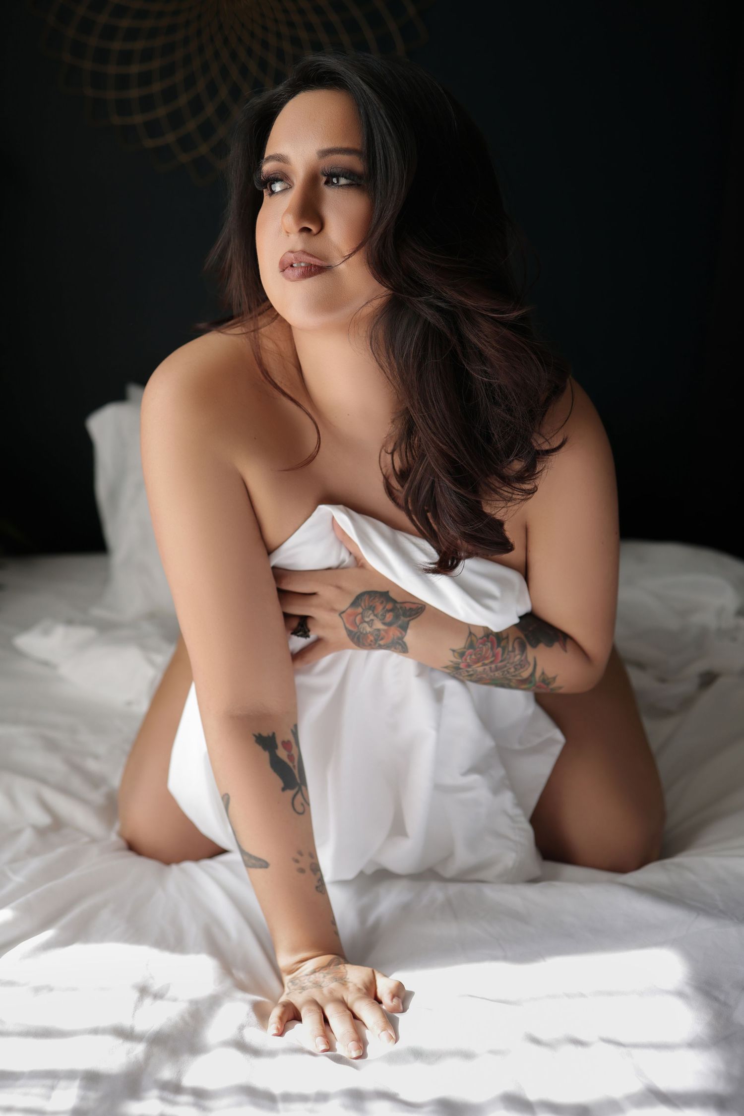 Intimate portrait of a woman posing in white bedding at a boudoir studio