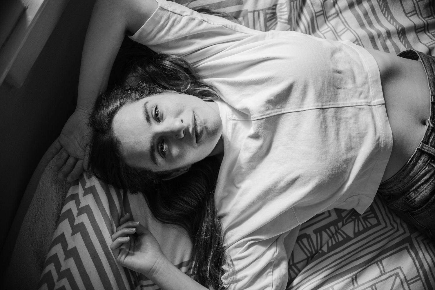 Person reclining on striped bedding in casual indoor photoshoot.