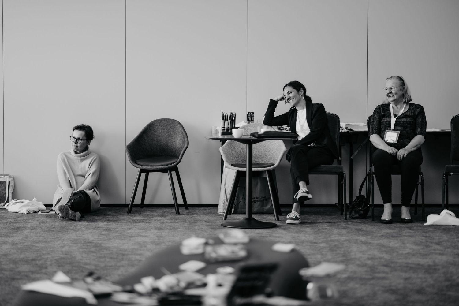 Black and white image of people sitting casually in a meeting space with modern furniture.