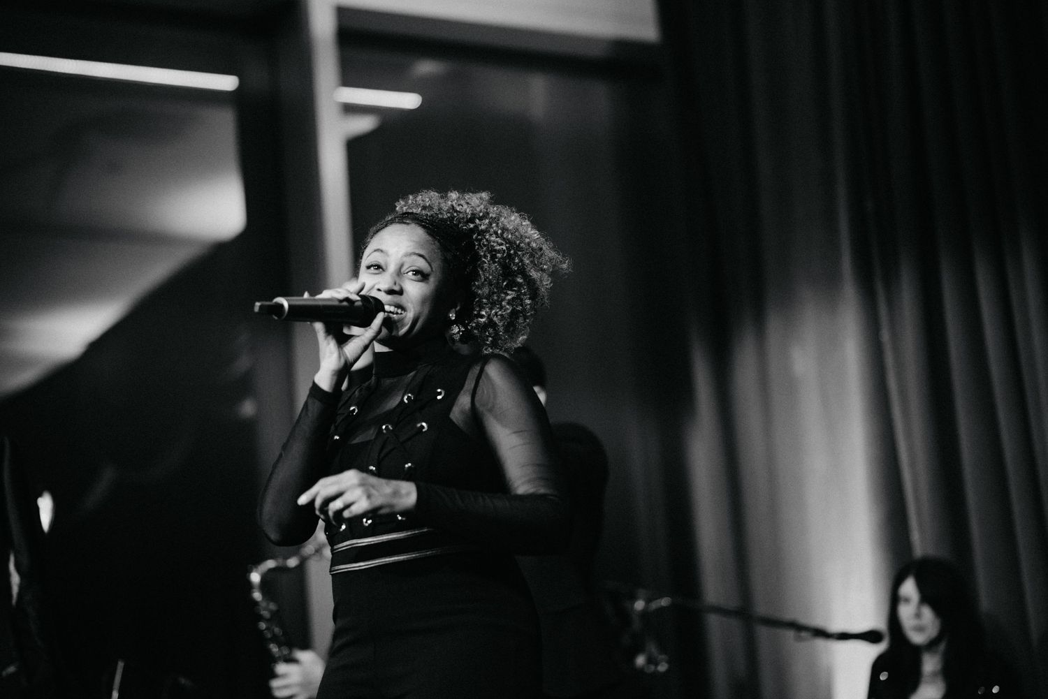 Black and white photo of a performer singing on stage with dramatic lighting.