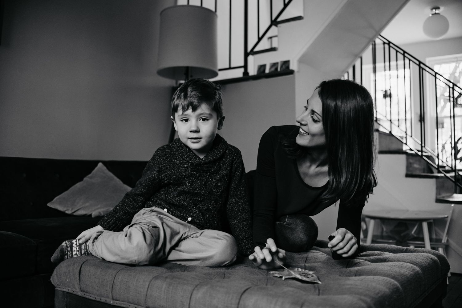 A monochrome image depicts a child and mother lounging together on furniture.