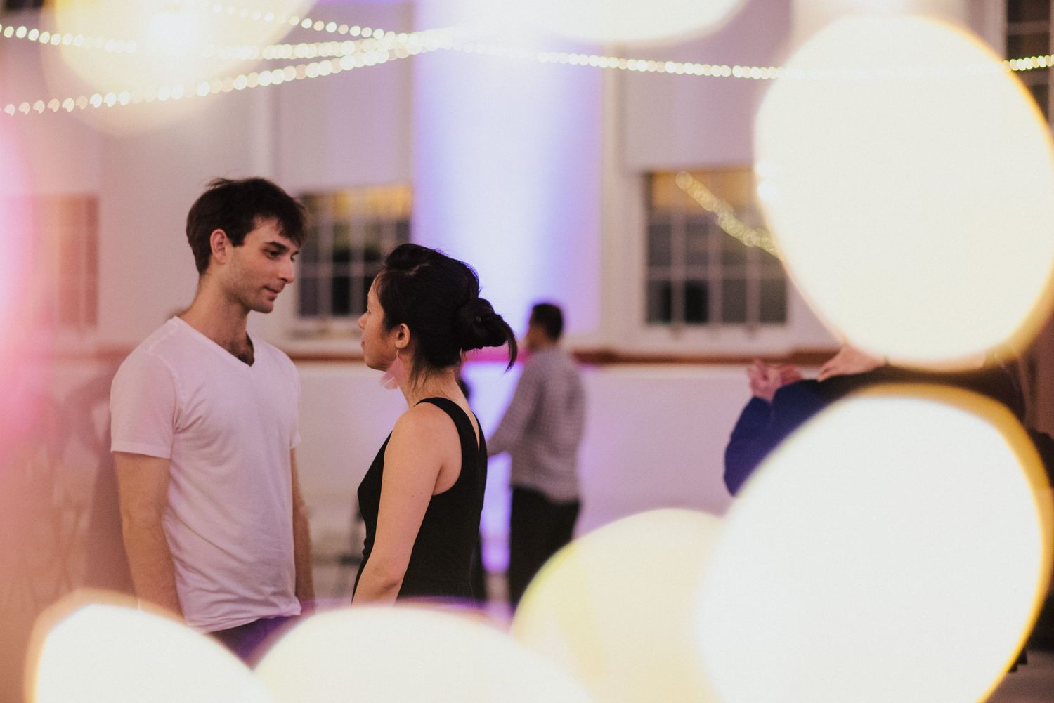 Soft focus photo of dancers in a studio with glowing orb lights.