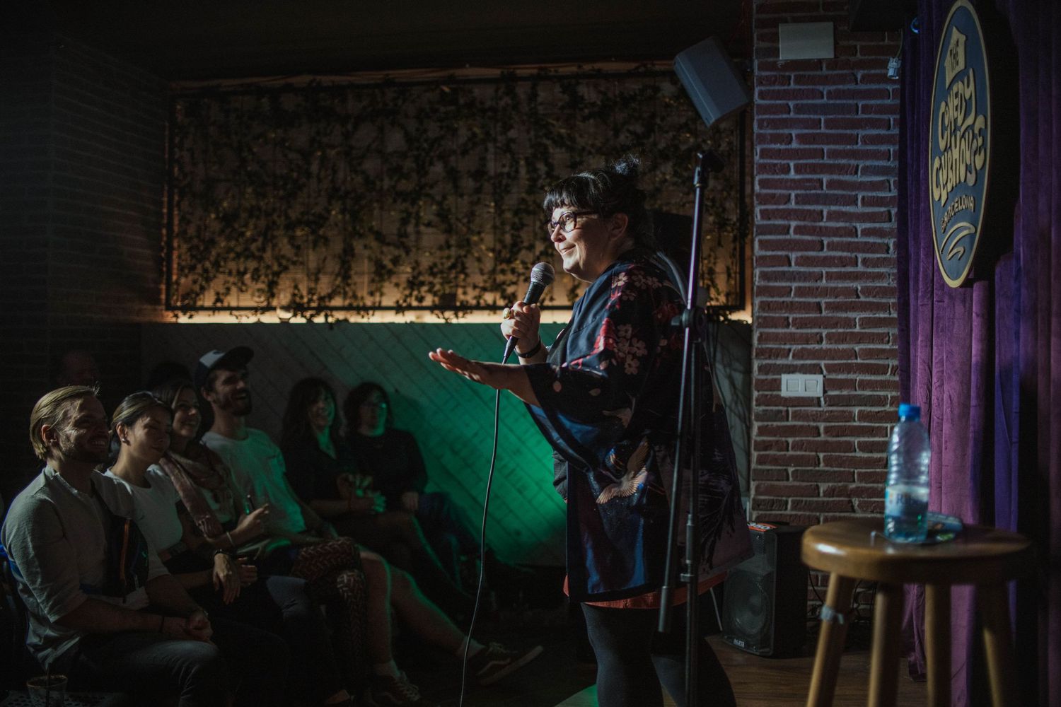 Comedy club interior with brick walls and stage lighting.