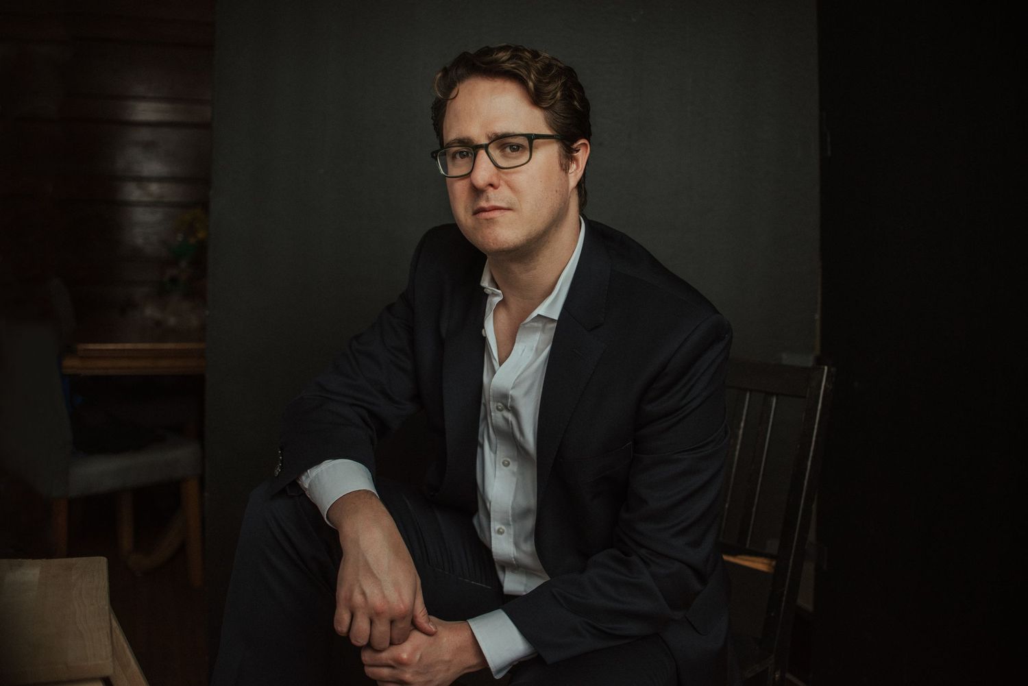 Professional portrait series showing contemplative poses against dark background in formal attire.