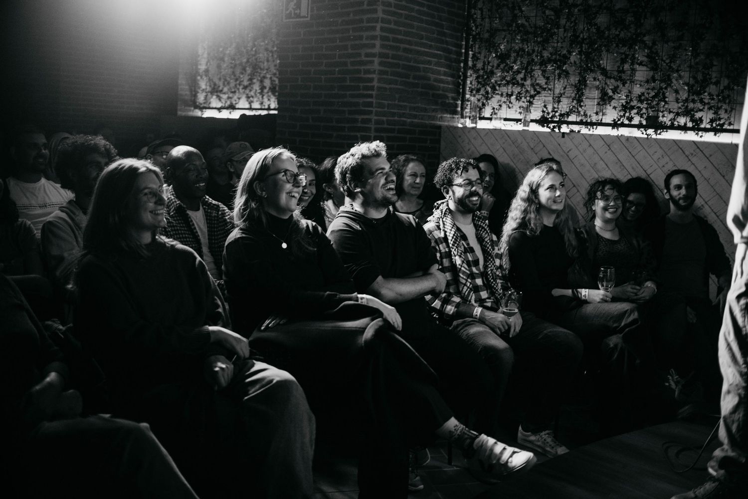 Audience members seated in rows at a dimly lit comedy show venue.