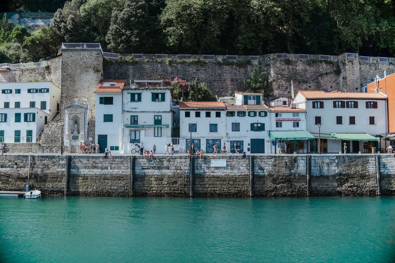 Panoramic view of colorful coastal houses along a turquoise waterfront in Menorca, Spain.