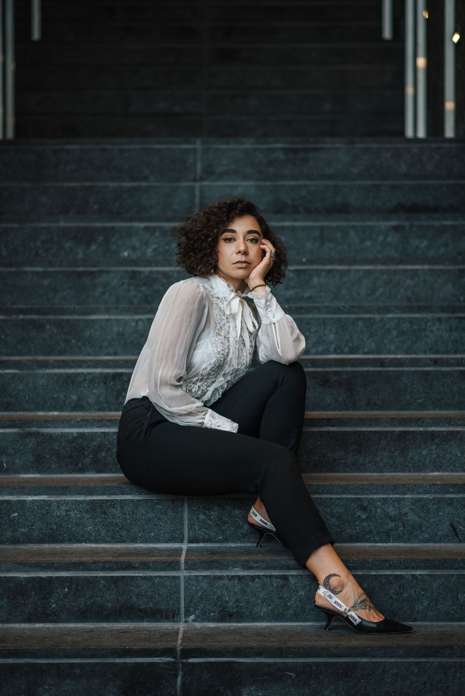 Person in vintage-style outfit reclining on dark stone steps.