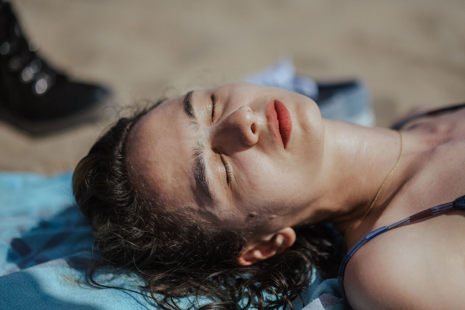 Person with wet hair and closed eyes lying in shallow water in artistic portrait series.
