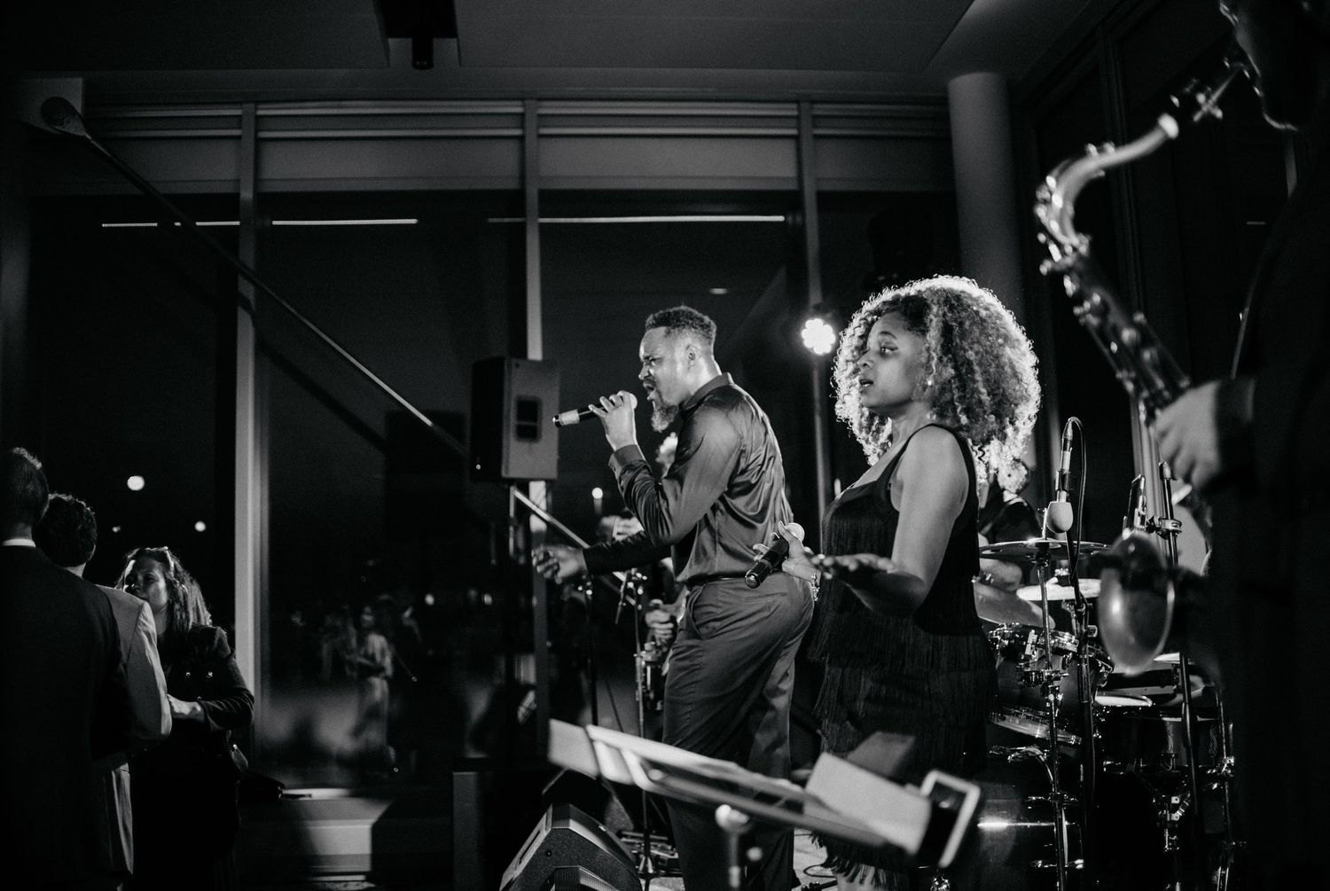 Black and white photo of band performing live on stage with instruments.