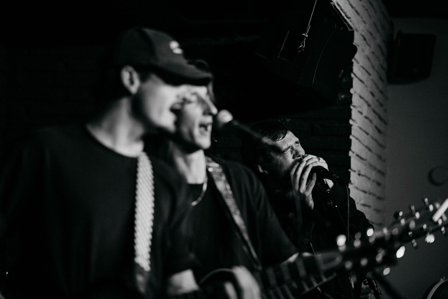 Musicians performing with guitars in moody black and white lighting.