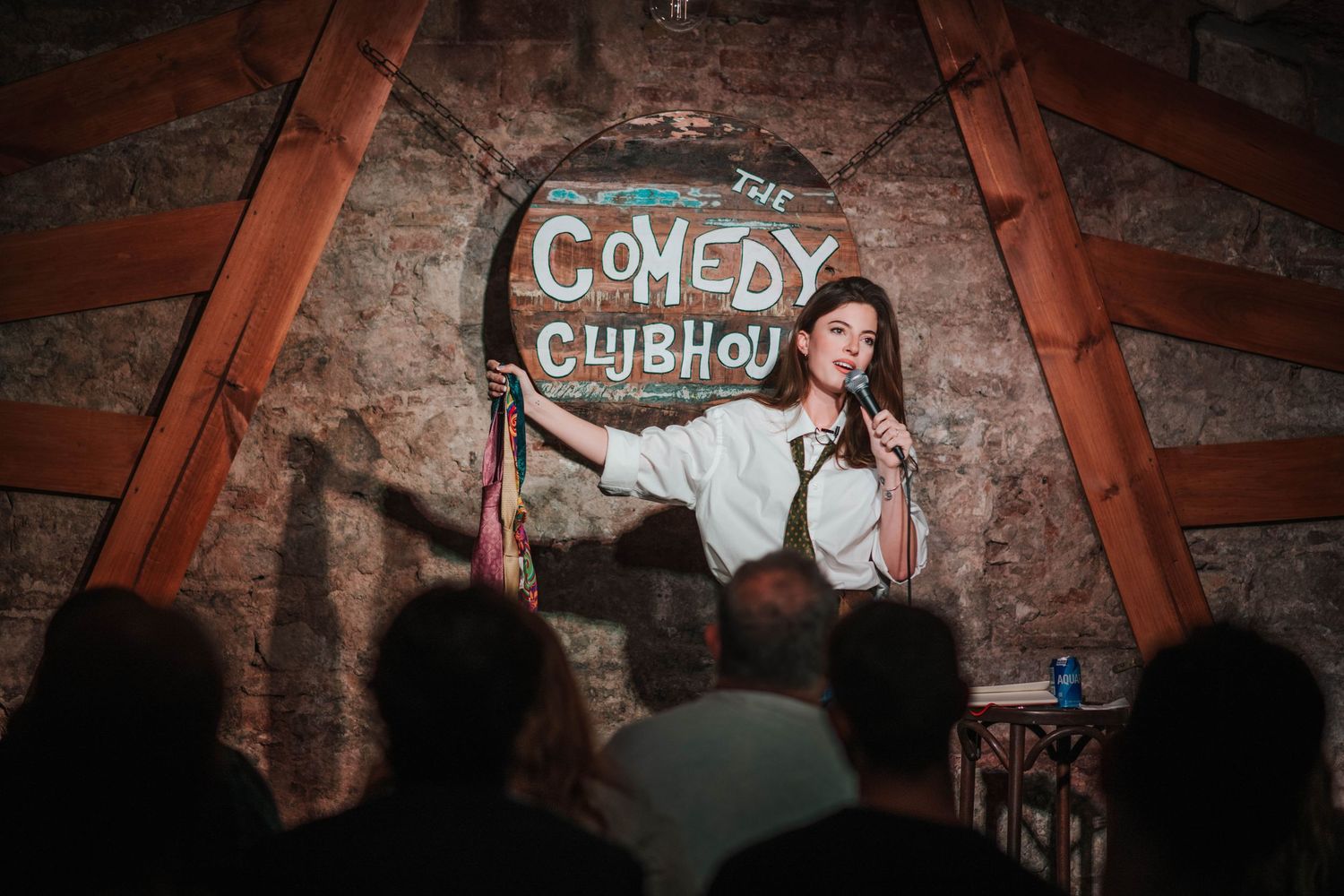 Comedy club stage with brick wall backdrop and spotlights.