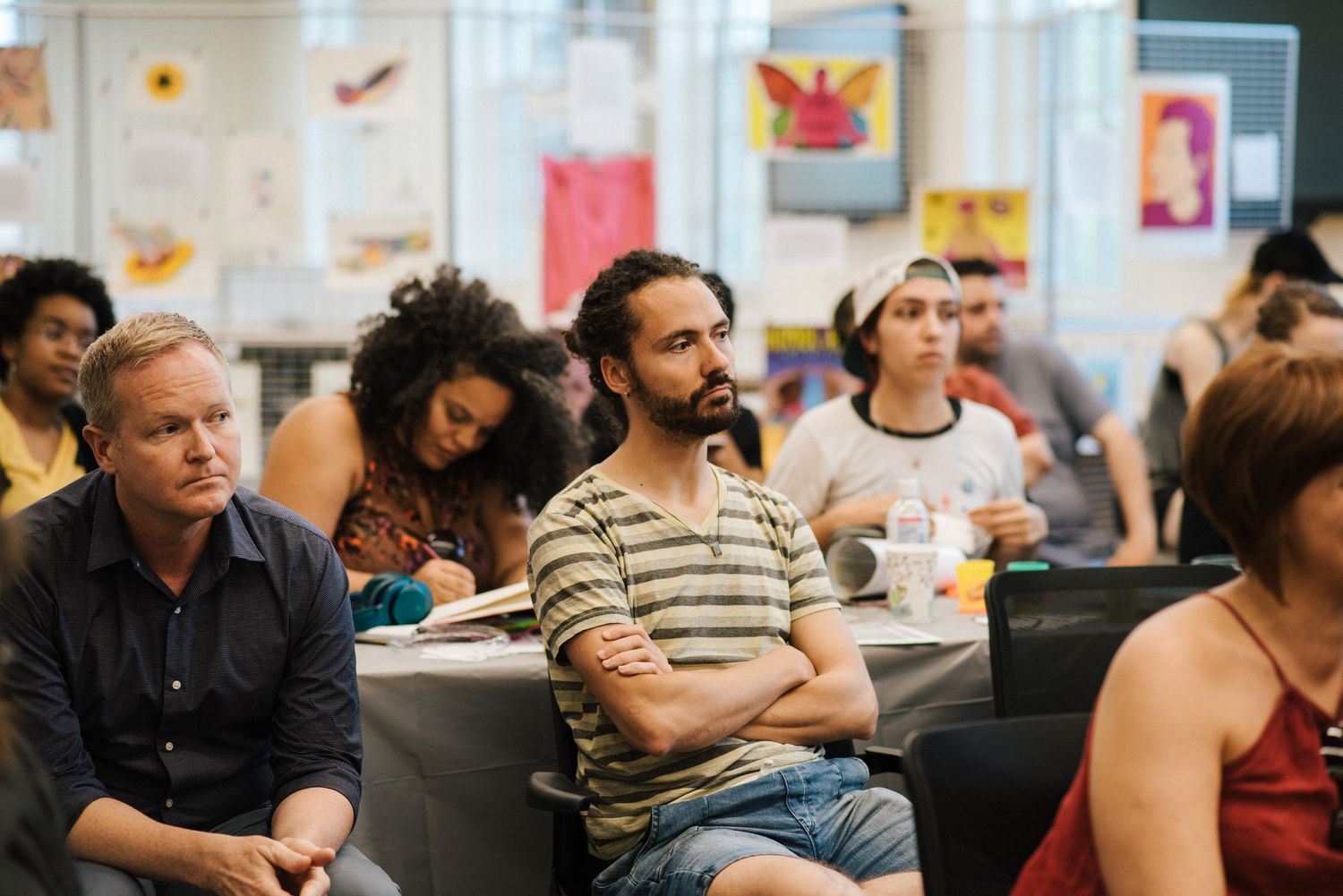 Diverse group of people attending a meeting or workshop in a bright indoor space.