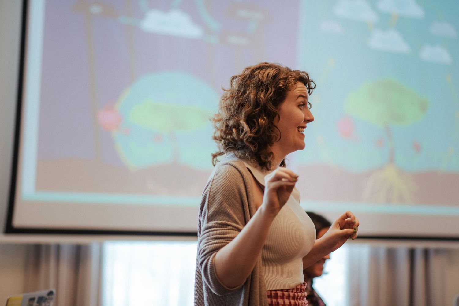 Presenter speaking animatedly in front of a projected presentation screen.
