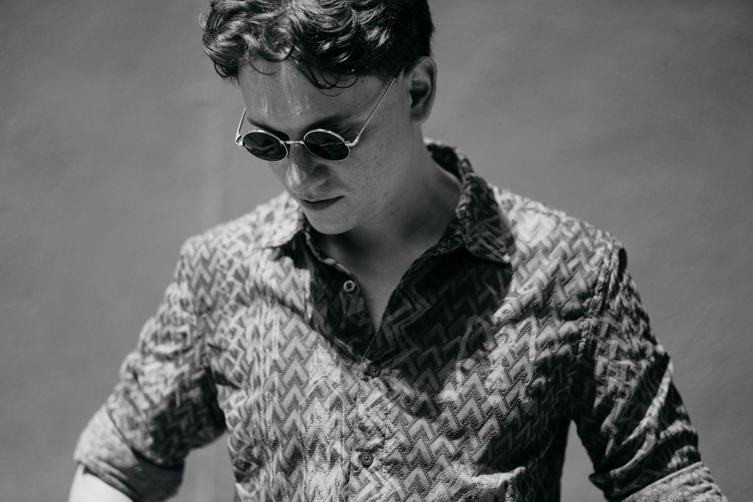 A black and white photo collage shows a person in a patterned shirt and sunglasses in various poses.