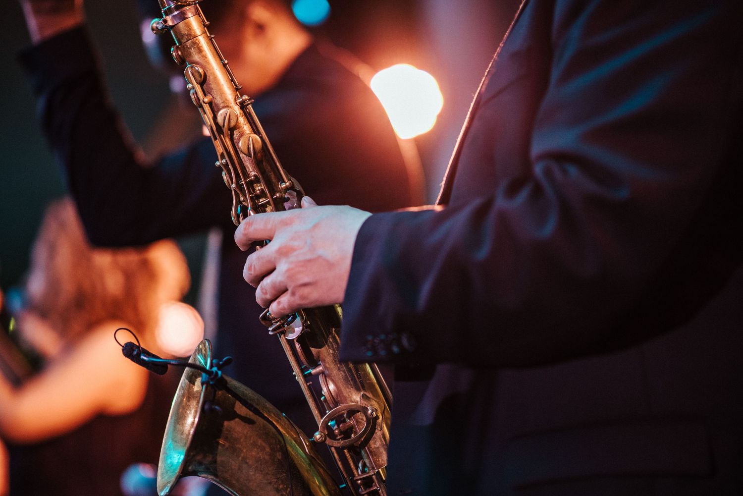 Close-up shot of saxophone player performing under stage lights.