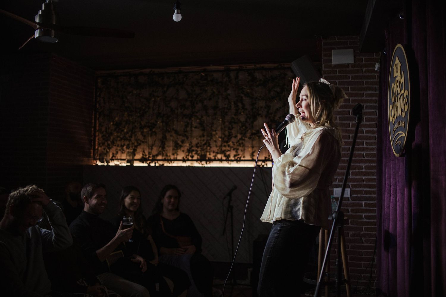Dimly lit comedy venue with stage lights and exposed brick walls.