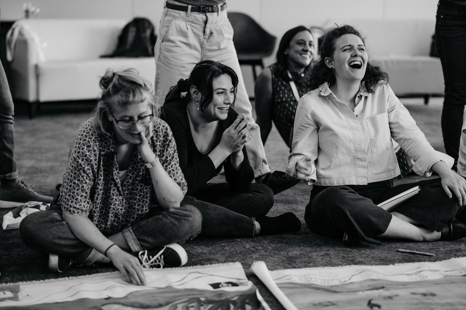 A black and white photo of people sitting together and sharing a lighthearted moment.