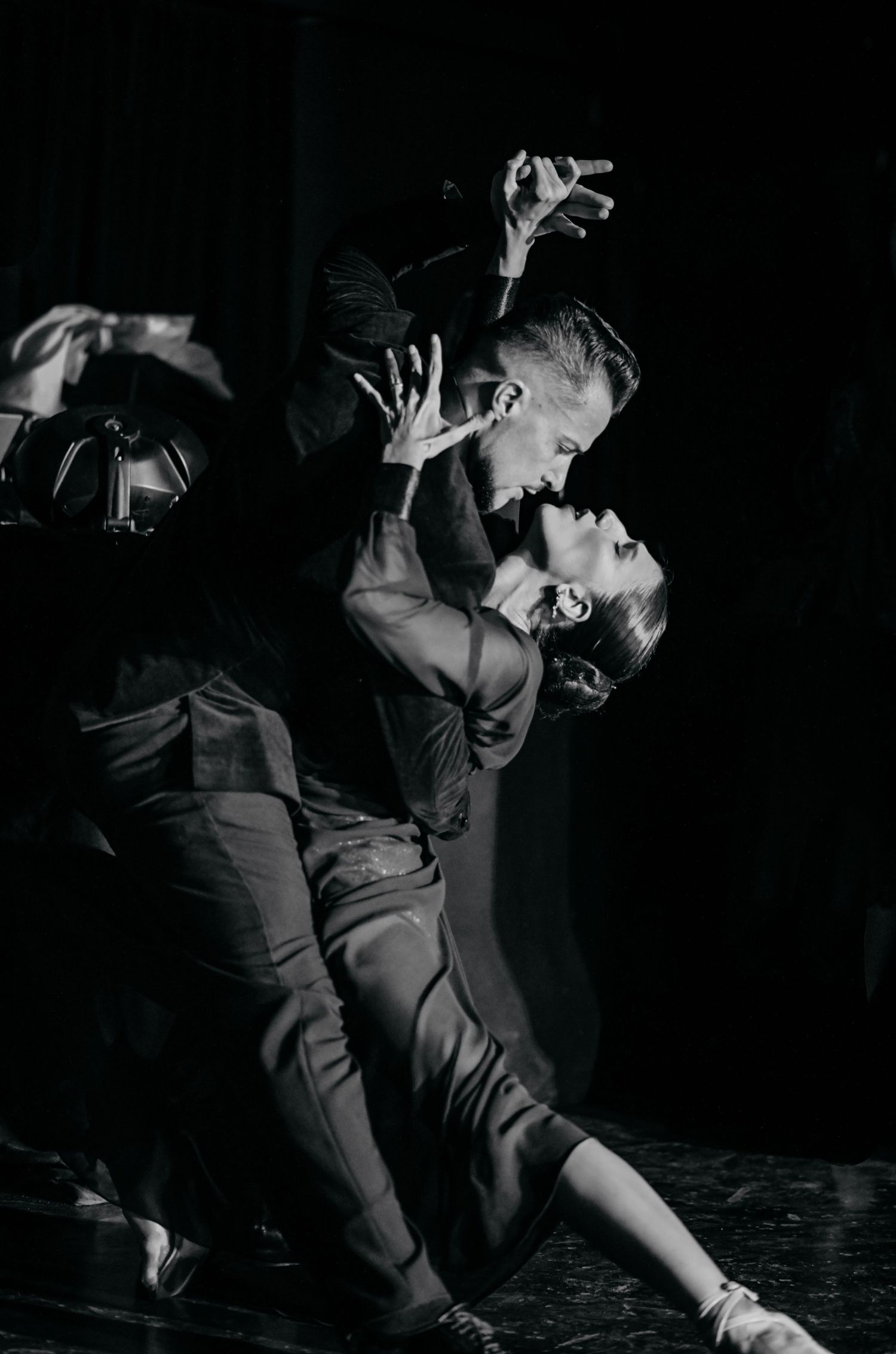 Black and white shot of dancers executing a dramatic dip move during a performance.