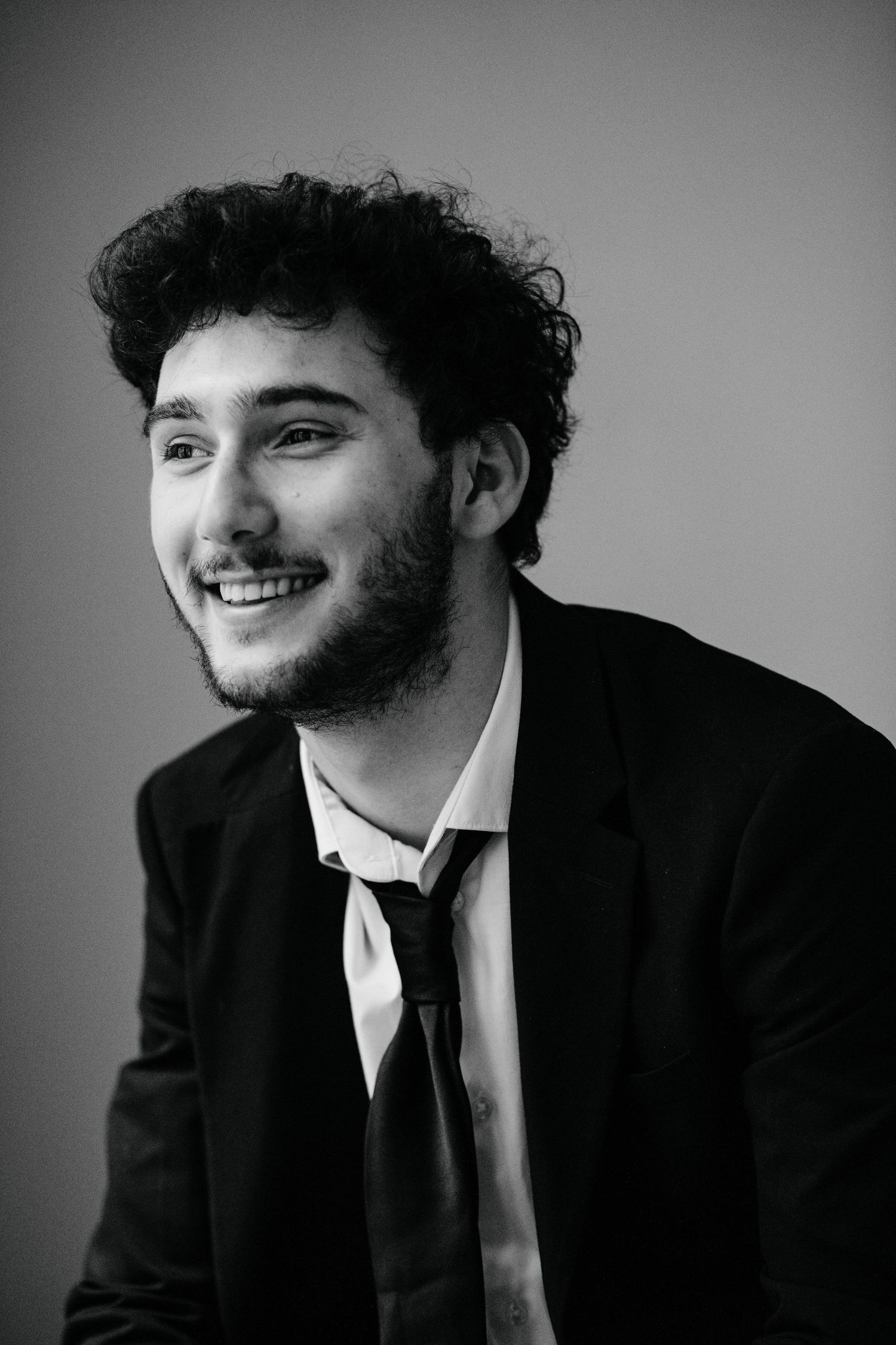 A series of black and white portrait photographs showing someone in a suit and tie against a simple background.