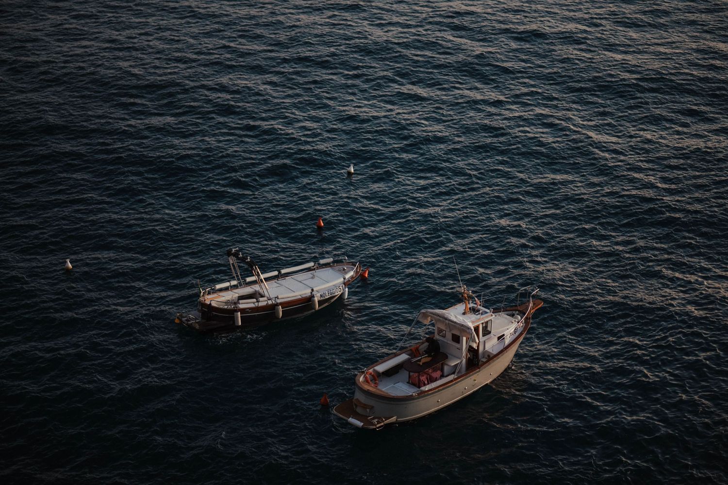Small boats float on dark rippling water against a moody seascape.