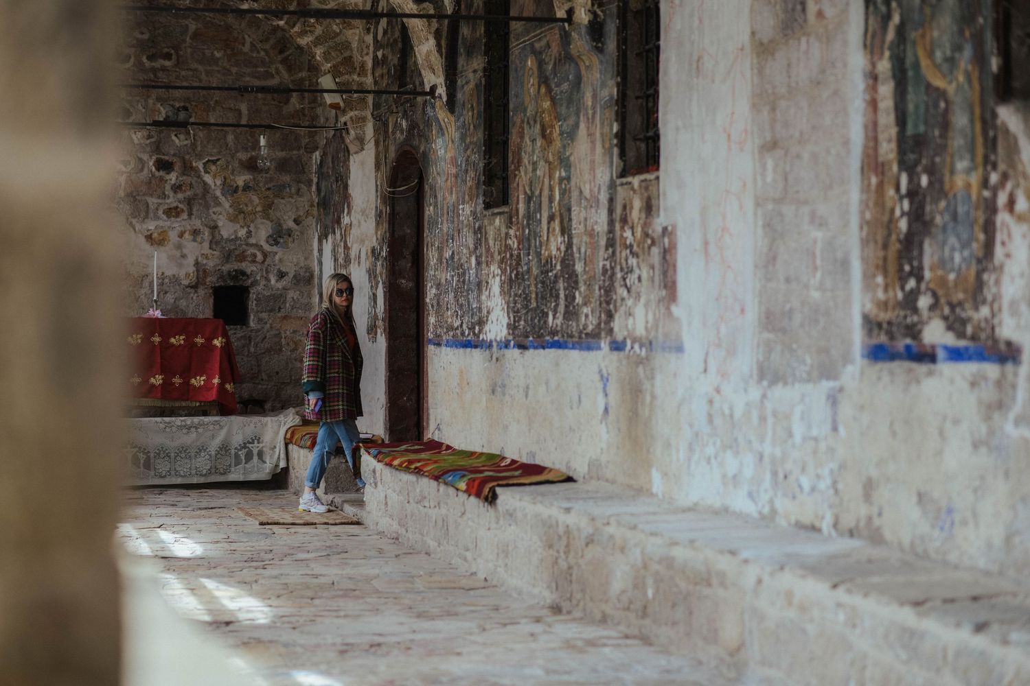 A long abandoned corridor in a decaying building shows peeling paint and deteriorating walls in dramatic lighting.