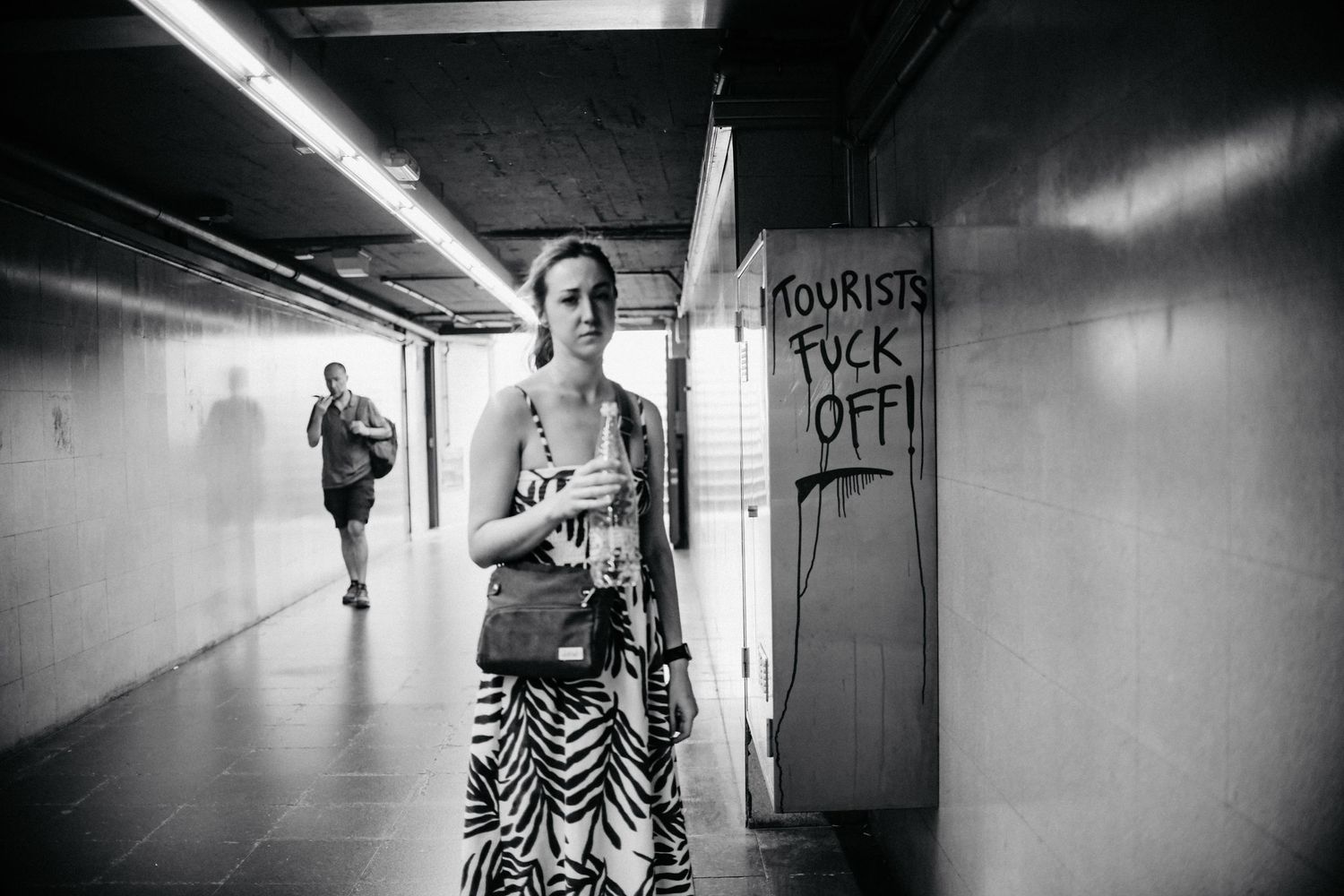 A black and white photo series showing people walking through dimly lit hallways and corridors.