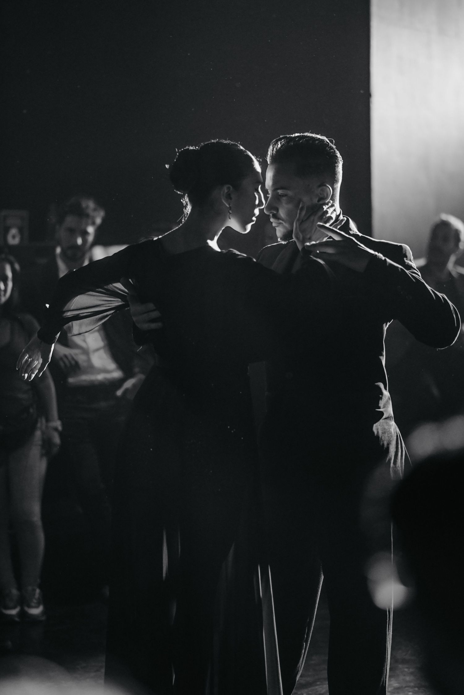 Silhouettes of couples dancing together in a dimly lit ballroom setting.