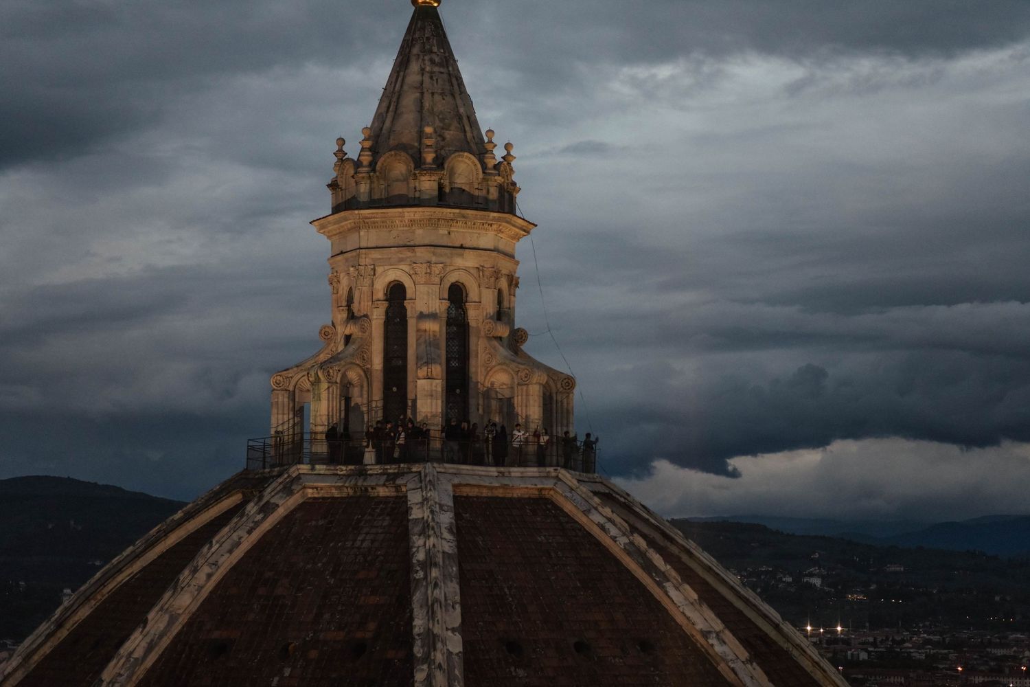 Gothic church spires silhouetted against dramatic stormy sky with dark clouds gathering overhead.
