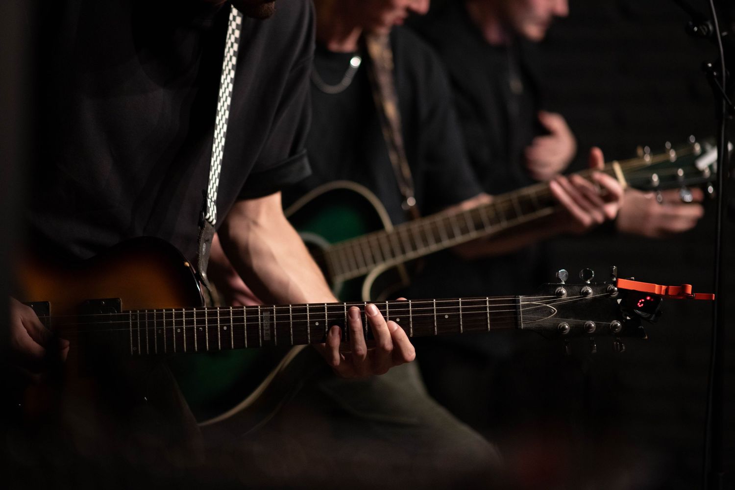 Close-up of hands playing acoustic guitar during dark stage performance.