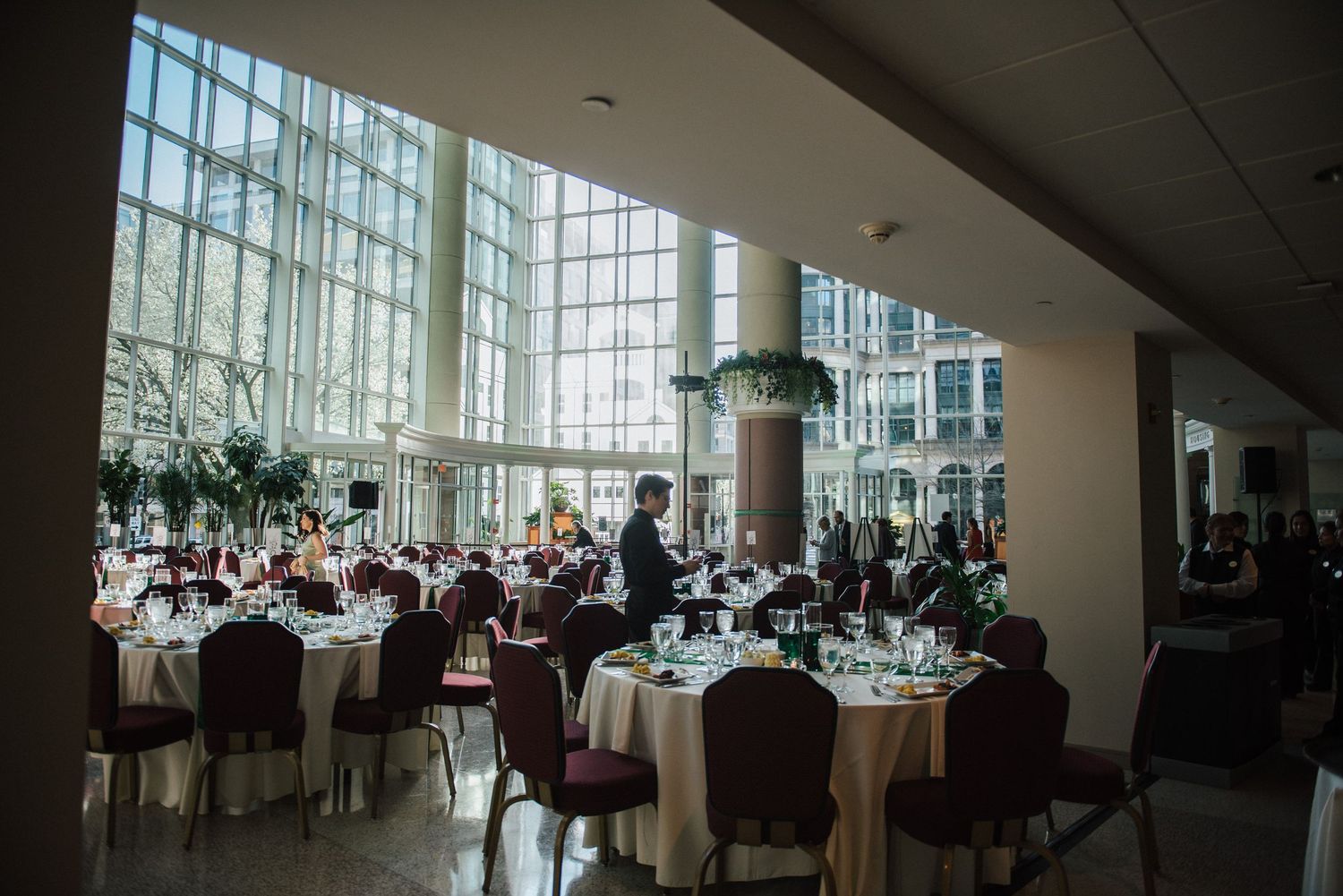 Large banquet hall with floor-to-ceiling windows and tables set for a formal event.